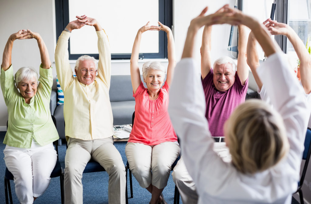 Seniors exercising and stretching in gym of senior community