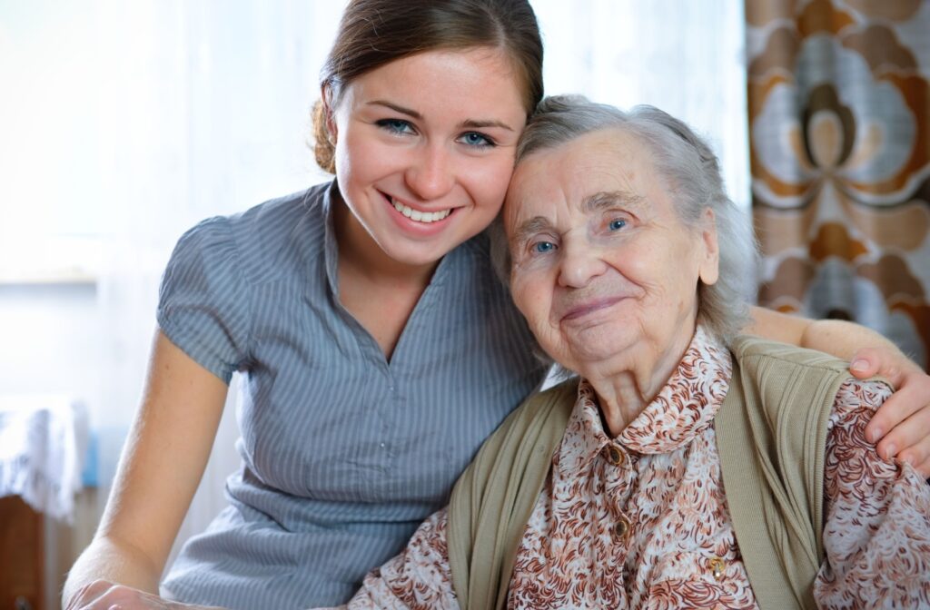 A smiling young woman embraces and leans her head against a happy, elderly woman.